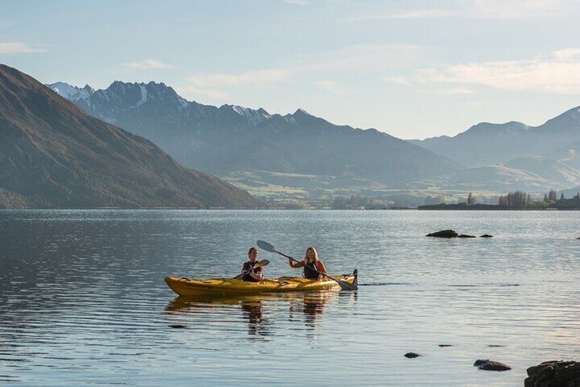 Dos personas haciendo kayak en un lago tranquilo con montañas al fondo. 2