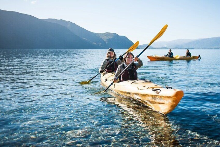 Personas haciendo kayak en un lago tranquilo con montañas al fondo. 4