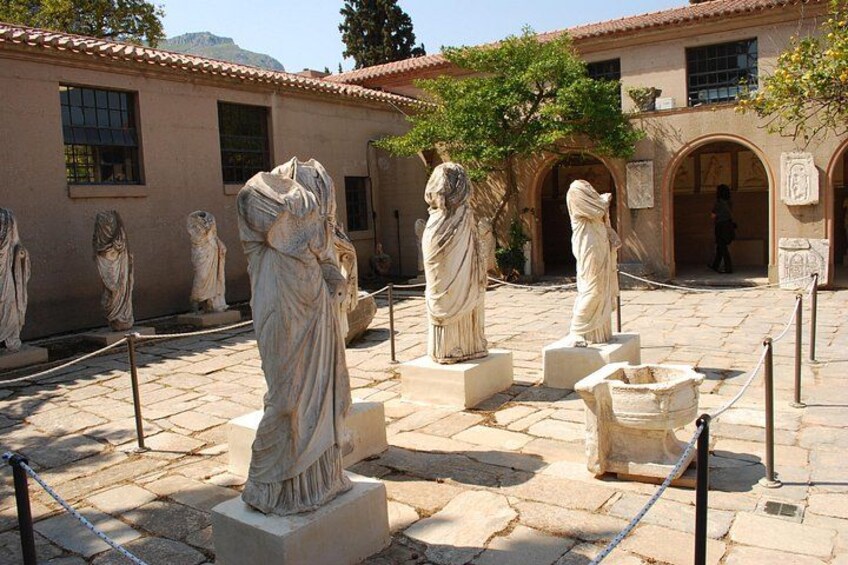A courtyard with classical statues and a building with arched doorways. 4