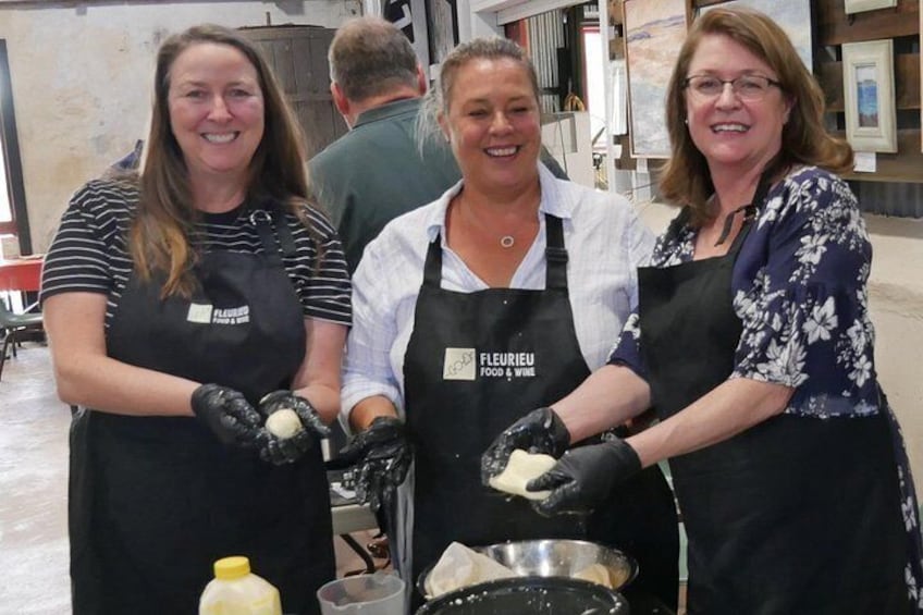 Three individuals wearing aprons and gloves, engaged in a food preparation activity. 4