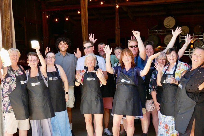 A group of people wearing aprons, standing in a room with wooden beams and a brick wall. 2