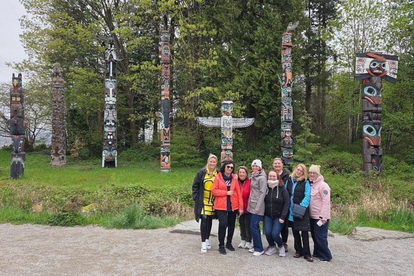 Un grupo de personas frente a totems con tallas complejas. 2