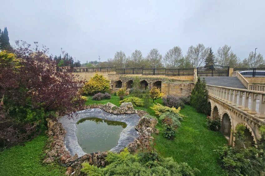 A garden with a pond, stone bridge, and lush greenery. 3