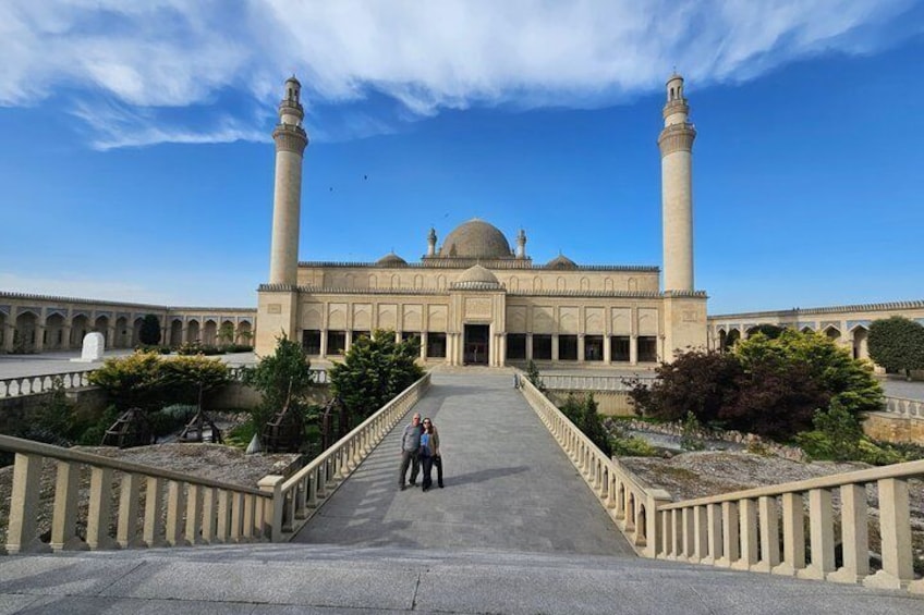A mosque with two minarets, a large dome, and a courtyard with a pathway leading to the entrance. 2