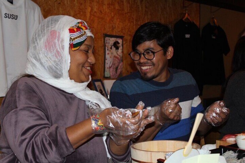 A person wearing a headscarf and gloves, holding a bowl with food. 5