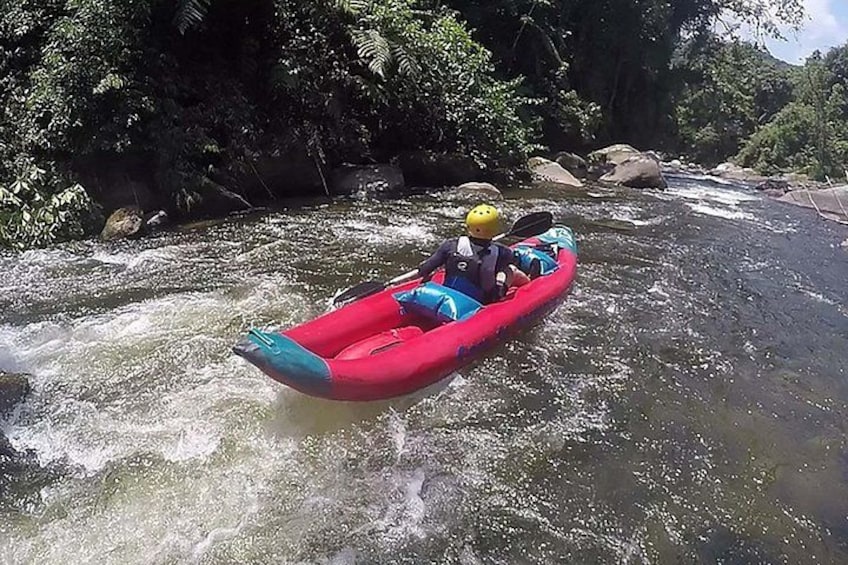 A person in a red kayak navigating a river surrounded by rocks and greenery. 4