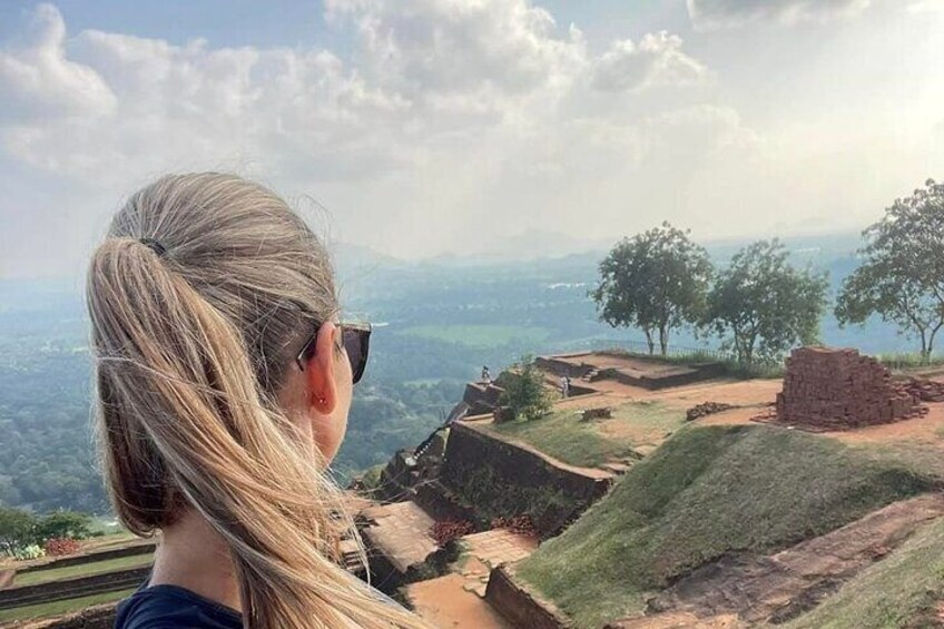 A person overlooking ancient ruins with a view of distant mountains and trees. 2