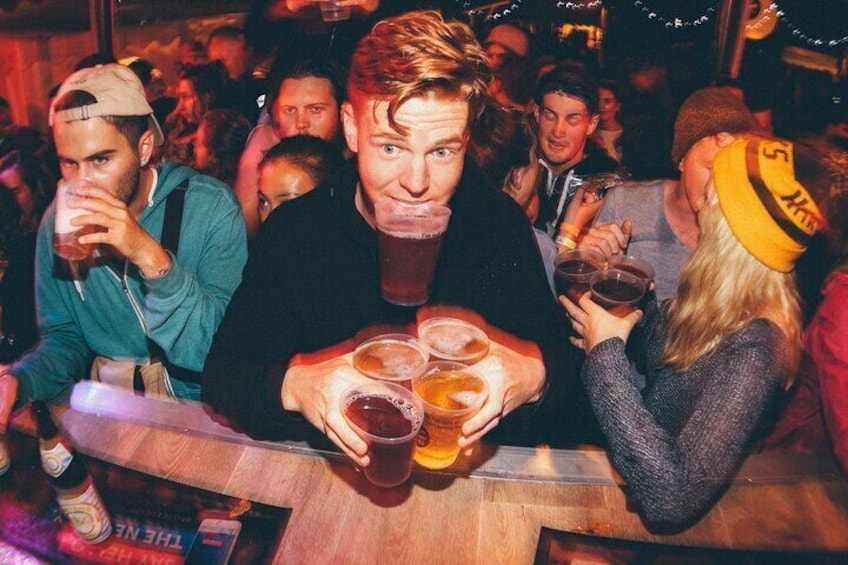 Eine belebte Bar mit Gästen, die Getränke halten. 5