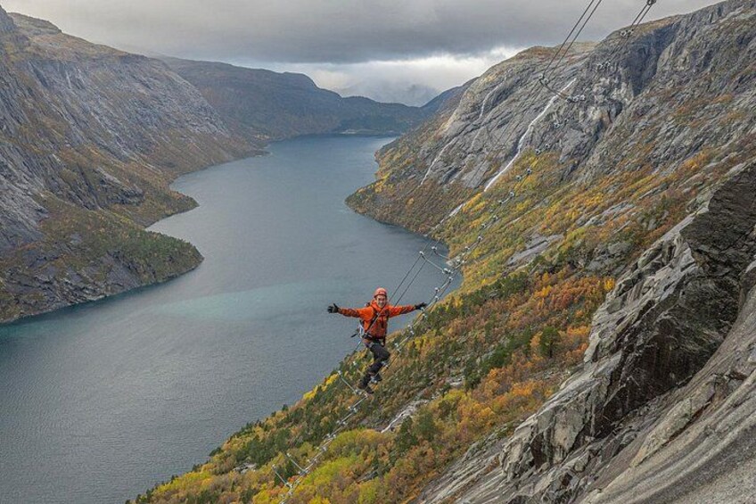 A person in an orange jacket on a mountain ridge with a lake below. 5