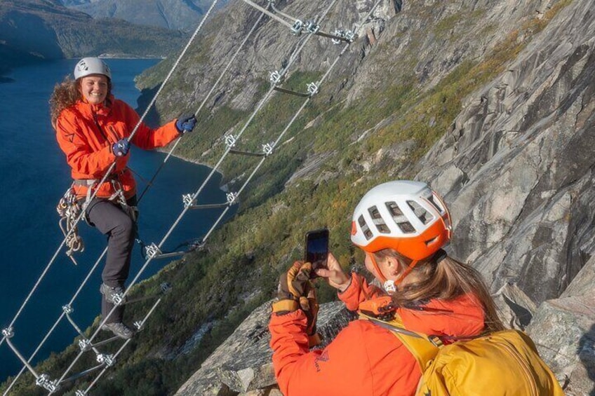 Two people rappelling down a mountain with a lake in the background. 2
