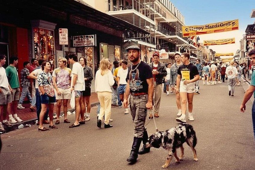 A crowded street with people walking, a dog on a leash, and a banner in the background. 2