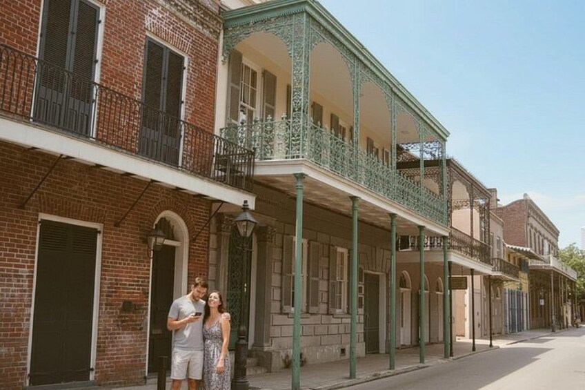 A historic street with brick buildings, green balconies, and a couple standing on the sidewalk. 5