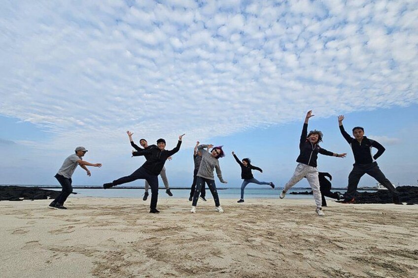 A group of people performing a dance on a sandy beach with a clear sky. 3