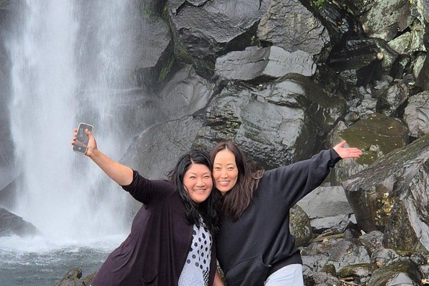 Two people taking a selfie with a waterfall in the background. 4