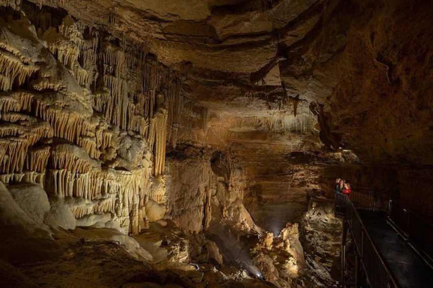 A cave with stalactites and stalagmites, a person in red, and a railing. 2
