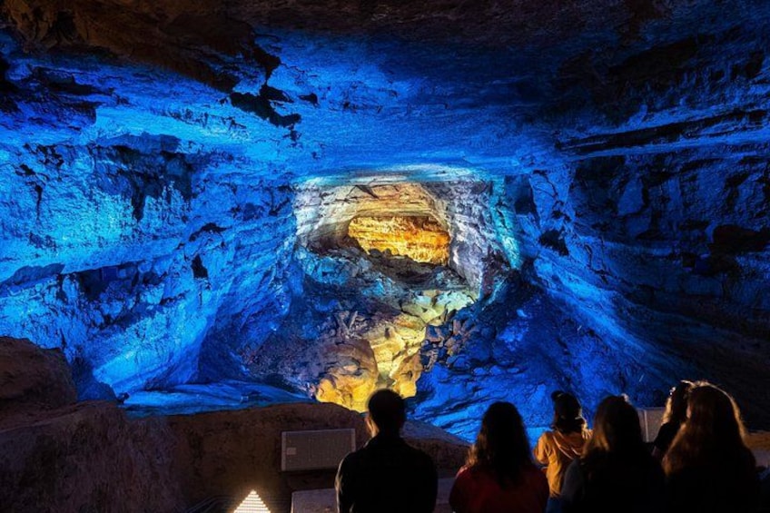 A cave with blue lighting and a central rock formation. 3
