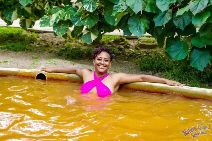 Une personne vêtue d’un maillot de bain rose, allongée sur un flotteur jaune dans une étendue d’eau, entourée de verdure. 5