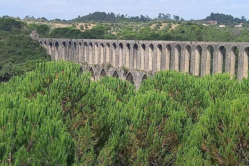 A stone viaduct with multiple arches, surrounded by green vegetation. 3