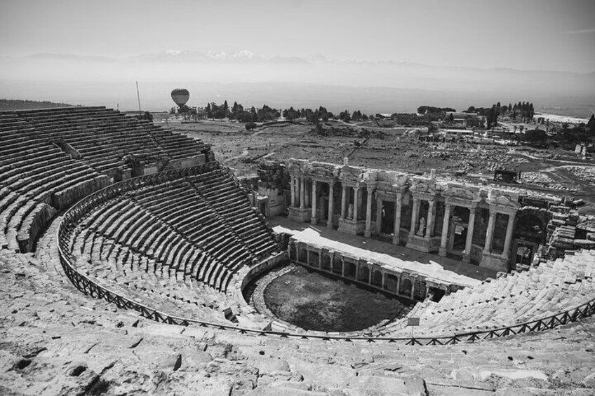 An ancient amphitheater with ruins and a large open area in the foreground. 3