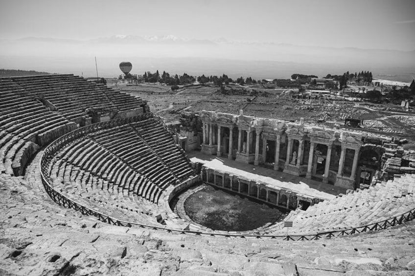 Un anfiteatro antiguo con asientos de piedra y ruinas en el centro. 2