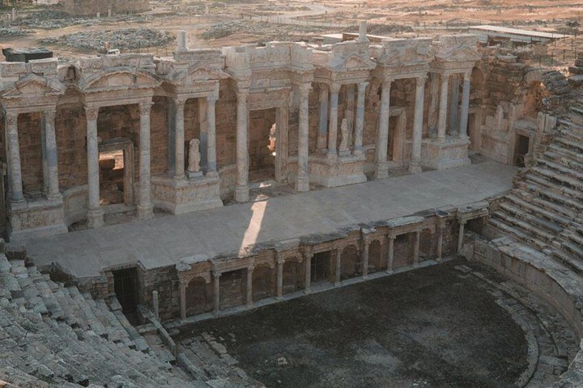 Un antiguo anfiteatro con asientos escalonados y columnas. 3