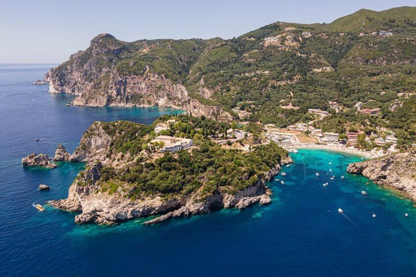 Eine Küstenlandschaft mit einer felsigen Insel, klarem türkisfarbenem Wasser und einer kleinen Siedlung. 1
