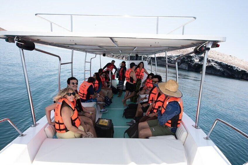 A group of people on a boat wearing life jackets, with rocky cliffs in the background. 2