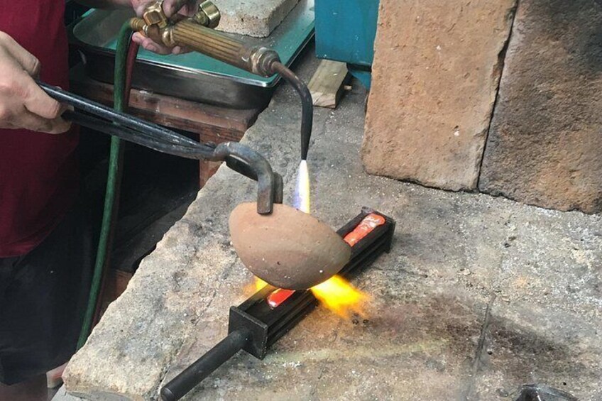 A person using a blowtorch to heat a metal object on a stone surface. 4
