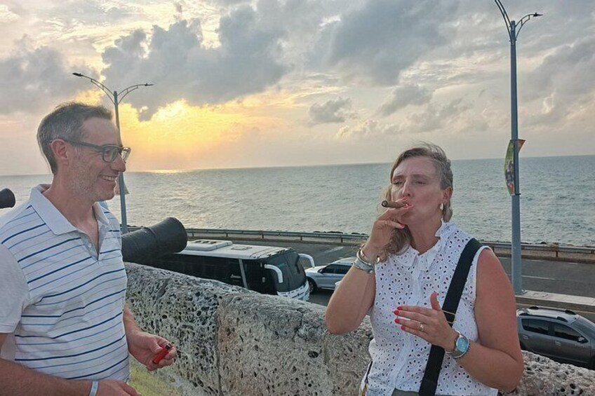 Two people standing by a waterfront, a sunset in the background, and a parked car. 5