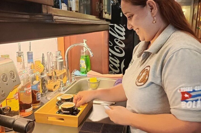 A person preparing food in a kitchen with various bottles and a Coca-Cola sign in the background. 2