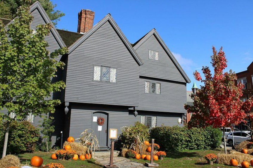 A two-story house with a gray exterior, a chimney, and a wreath on the door. 2