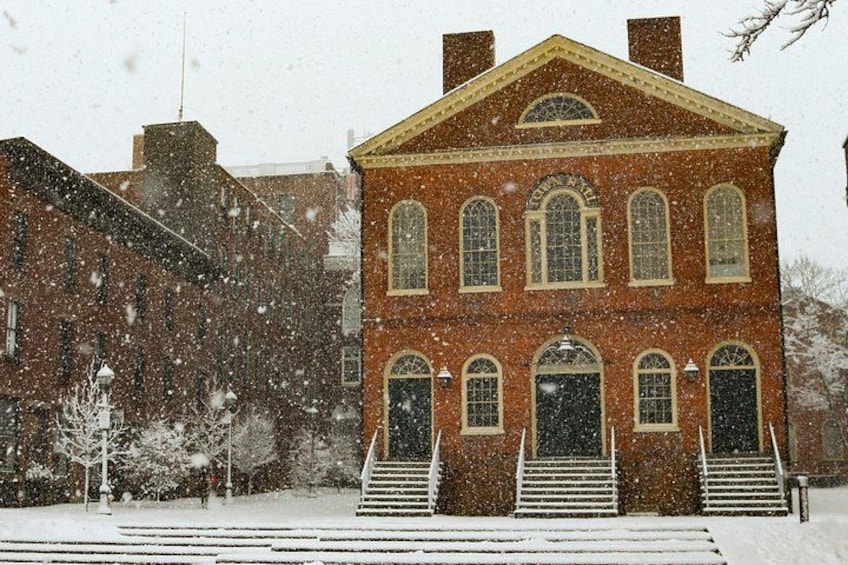 A snow-covered brick building with multiple windows and a central entrance. 4