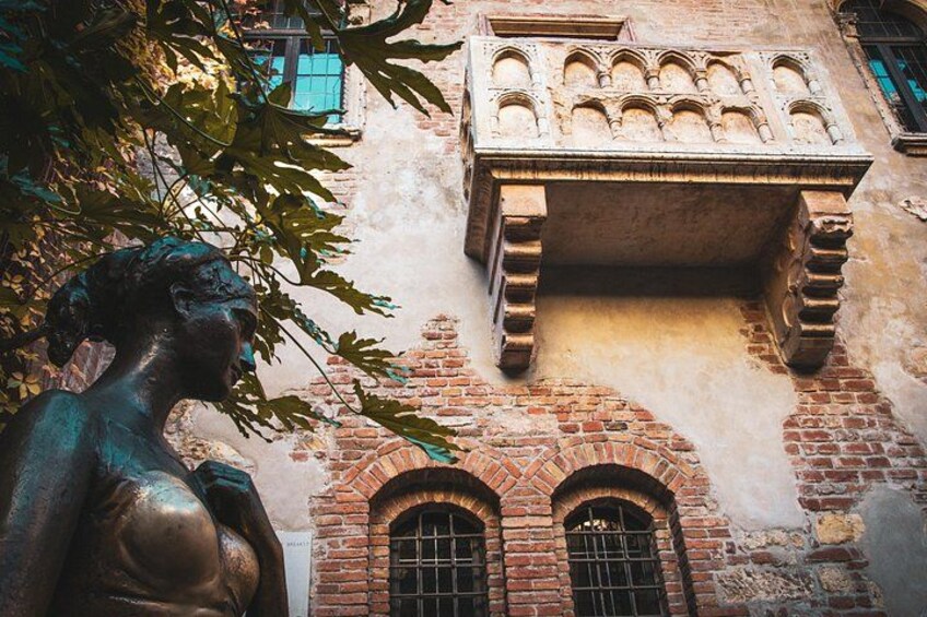 A statue of a woman, a brick building with arched windows, and a balcony with intricate carvings. 5
