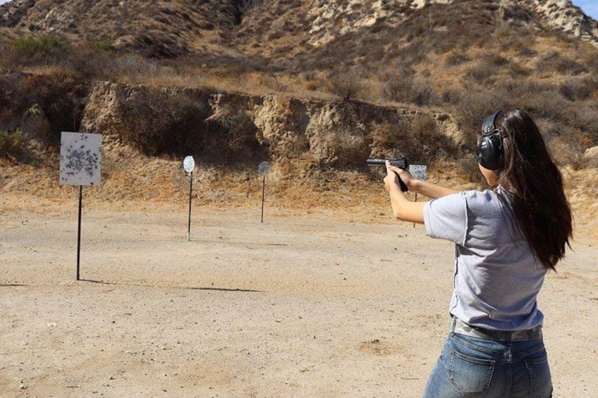 A person aiming a handgun at a shooting range with targets in the background. 5