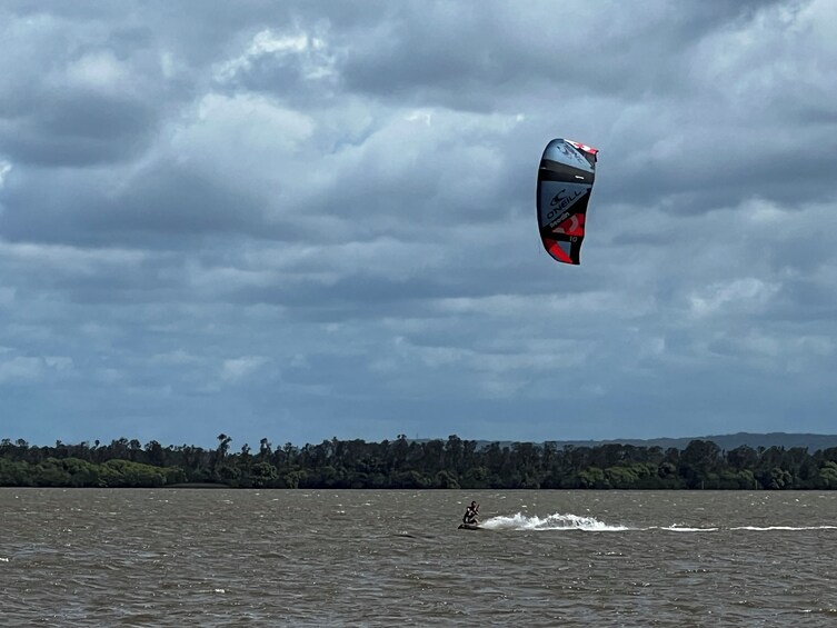 Una persona practicando kitesurf sobre una superficie de agua, con cielo nublado. 3