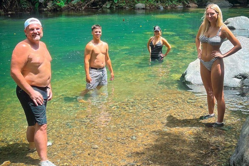 A group of people standing in a clear, shallow body of water surrounded by rocks. 1