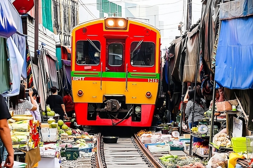 A colorful train with the number 1216 on a track surrounded by market stalls. 4