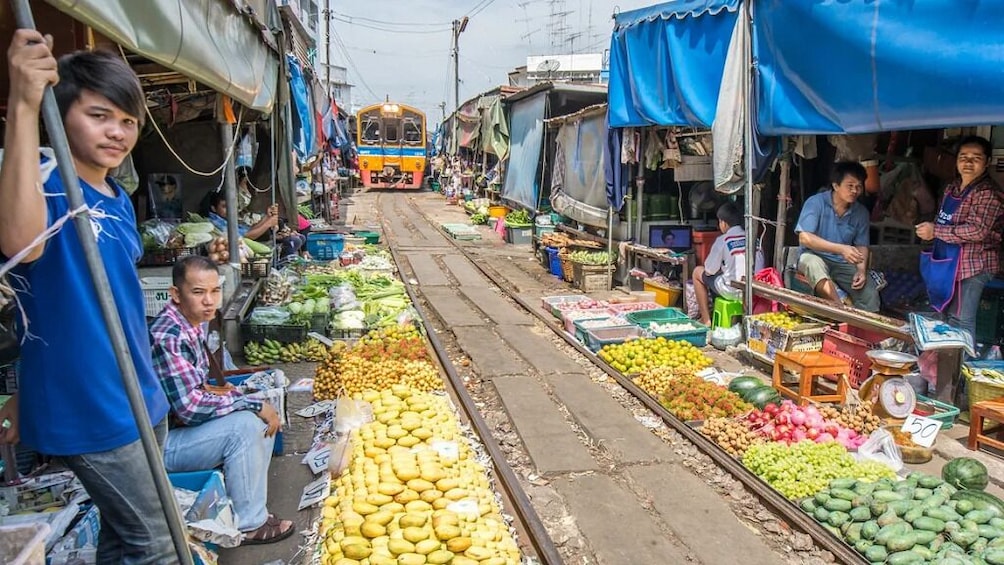 A bustling market with vendors selling fruits and vegetables along a railway track. 5