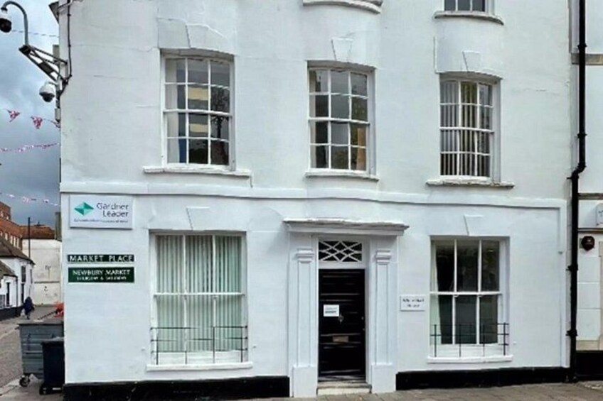 A white building with multiple windows and a sign that reads 'Market Place.' 2