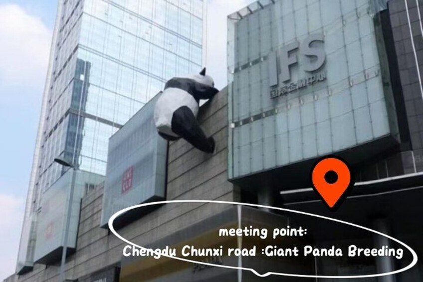 A building with a glass facade and a panda sculpture on the side. 2