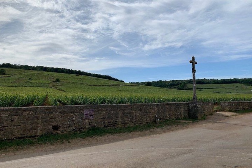 Una strada di campagna con un muro in pietra e una croce su un palo. 2