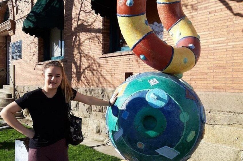 A person standing next to a colorful sculpture of a soccer ball with a human figure on top. 3