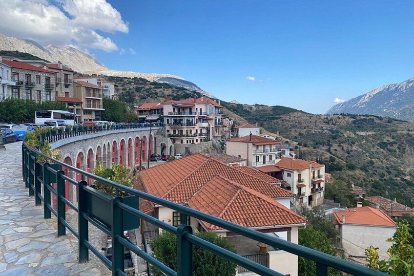 A hillside town with terraced houses, a stone pathway, and a mountain backdrop. 2