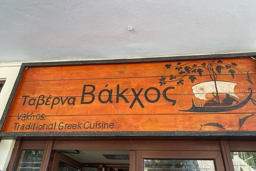 A wooden signboard with the name 'Tafepva Bakxoc' and the words 'Vakhos. Traditional Greek Cuisine' written on it. 5