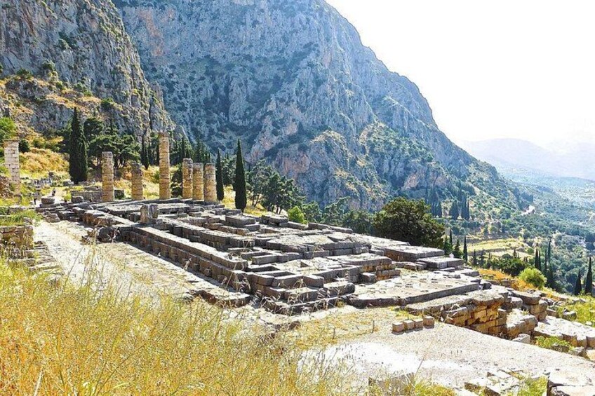 Ancient ruins with columns and stone structures, set against a mountainous backdrop. 5