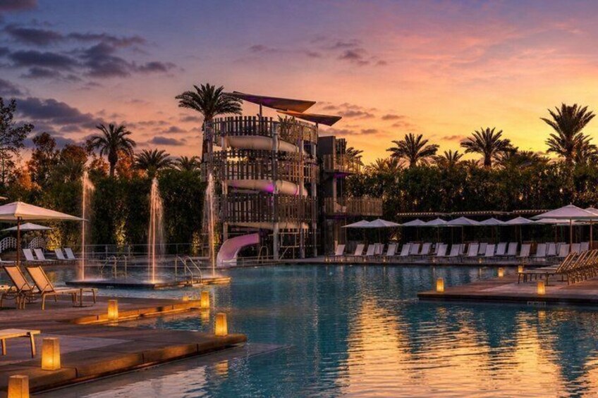 A swimming pool with lounge chairs, a water slide, and a sunset. 3