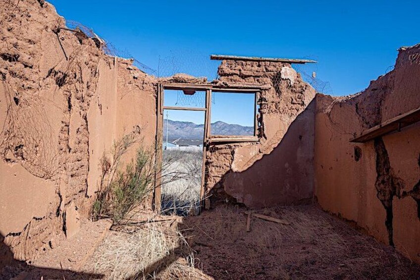 A dilapidated building with a broken window and a view of mountains. 3