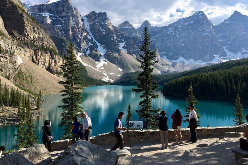 Un groupe de personnes se tient près d’un lac, avec des montagnes en arrière-plan. 5