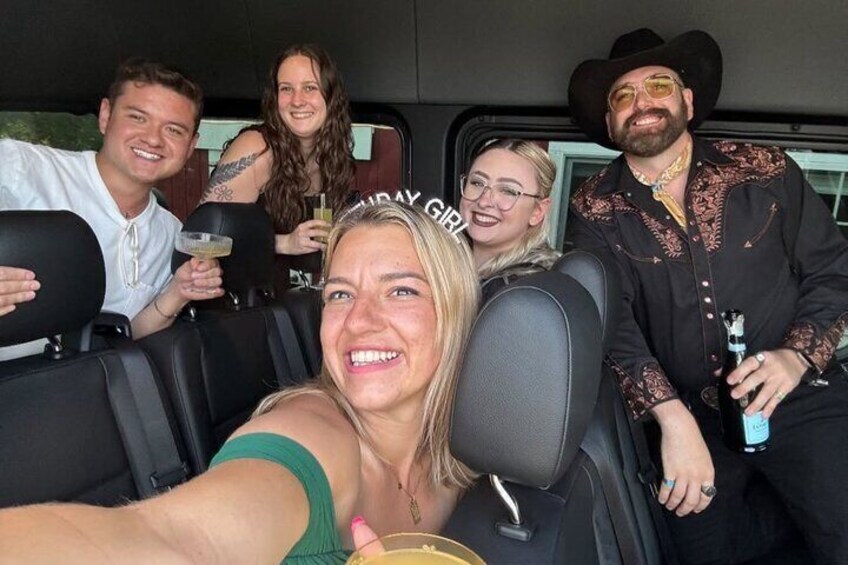 A group of people in a vehicle, some holding drinks. 1