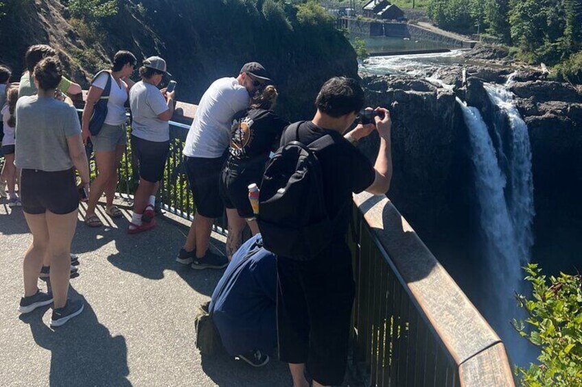 People standing on a bridge, taking photos of a waterfall. 3